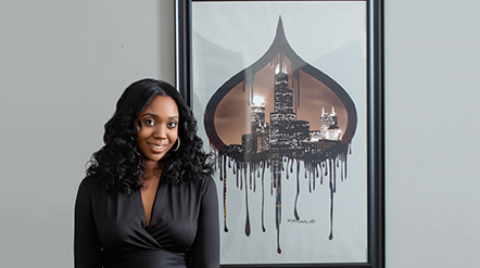 Next Gen MBA student Nikiya Price smiling next to a piece of art. Next Gen MBA student Nikiya Price smiling next to a piece of art.